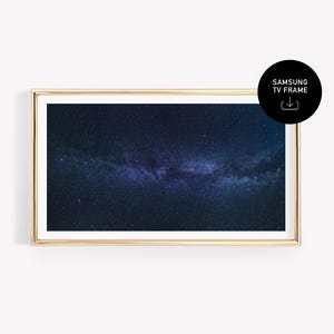 以下が含まれることがあります： 夜空の濃い青と紫色の描写が施された、長方形の金色のフレームアートプリント。プリントには白い縁取りがあり、「SAMSUNG TV FRAME」というテキストとダウンロードアイコンが付いた黒い円があります。