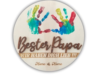 May include: A round wooden sign with two colorful handprints painted on it. The sign says "Bester Papa" and "Wir haben dich lieb!!!" with the names "Name & Name" at the bottom.
