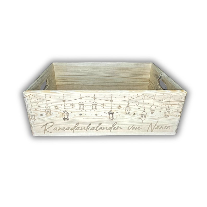 Op de afbeelding: Een houten doos met een lichtbruine afwerking en een gegraveerd ontwerp van lantaarns en sterren. De tekst "Ramadan calendar von Name" is gegraveerd op de onderkant van de doos.