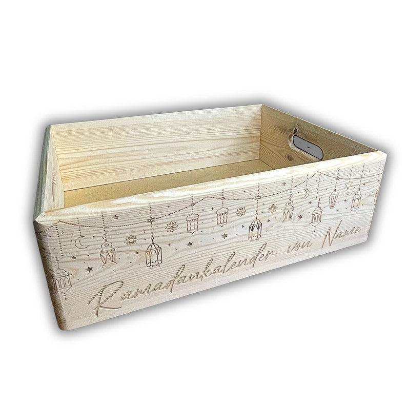 Op de afbeelding: Een houten doos met een Ramadan-kalenderontwerp. De doos is gegraveerd met de woorden "Ramadankalender von Name" en heeft een slinger met lampionnen en sterren.