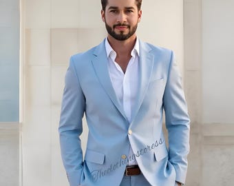 May include: A light blue suit with a white dress shirt. The suit has a two-button closure and a notched lapel. The model is wearing a brown belt. The clothing store's logo is visible on the suit.