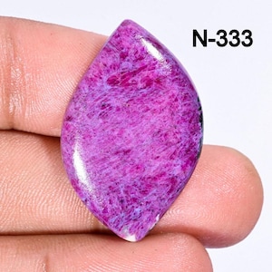 May include: A purple and white cabochon gemstone with a swirling pattern. The gemstone is shaped like a teardrop and has a smooth, polished surface. N-333