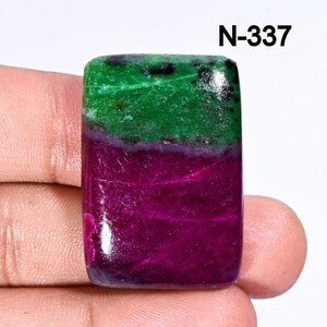Könnte beinhalten: Ein grüner und violetter Edelstein-Cabochon in rechteckiger Form. Der Stein hat eine geschichtete Optik mit einer grünen oberen Schicht und einer violetten unteren Schicht. Der Stein ist mit der Nummer N-337 gekennzeichnet.