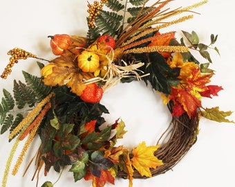 May include: A fall-themed wreath with a brown grapevine base, decorated with faux leaves in shades of orange, yellow, and green, along with small faux gourds and berries.