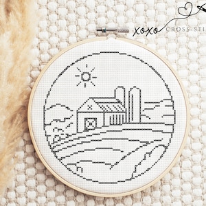 Puede incluir: Bordado de punto de cruz en blanco y negro de una granja con un silo, colinas y un sol en un aro circular.