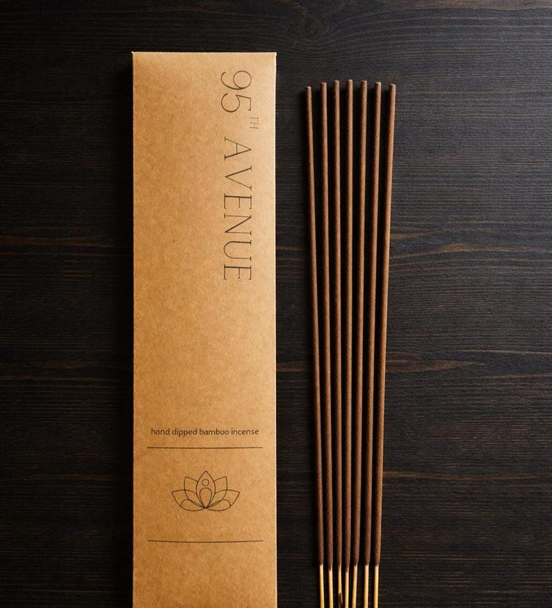 May include: A brown package of hand-dipped bamboo incense with the text "95th Avenue". The package has a lotus flower graphic. The incense sticks are brown with gold tips. The background is dark.