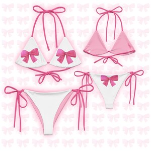 May include: White bikini with pink bow details. The top is a triangle style with adjustable straps and the bottom is a cheeky style with ties on the sides.