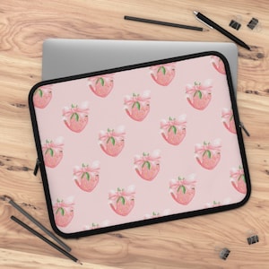 May include: Pink laptop sleeve with a repeating pattern of pink strawberries with white bows.