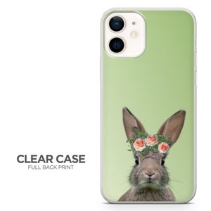 May include: A clear phone case with a full back print of a brown rabbit wearing a flower crown with pink flowers and green leaves on a light green background.