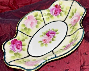 Plato ovalado antiguo Nippon con borde festoneado, estampado floral rosa con puntos dorados y ribete negro.