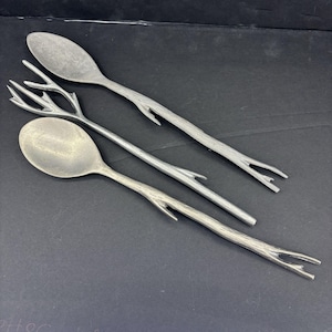 May include: Three silver-toned serving utensils with a branch-like design. The utensils are a spoon, a fork, and a serving spoon.