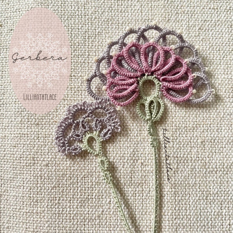May include: A tatting lace applique featuring two floral motifs with stems. The larger flower has pink petals and a grey outer ring with small white beads. The smaller flower is light purple. Both have light green stems and intricate thread loops.