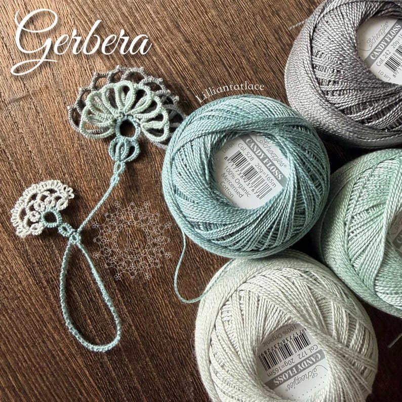 May include: Four balls of Scheepjes Candy Floss 100% organic mercerised cotton yarn in shades of grey, light blue, and pale green, alongside a delicate, hand-crocheted lace motif featuring a fan-like design and a thin, looped thread tail.