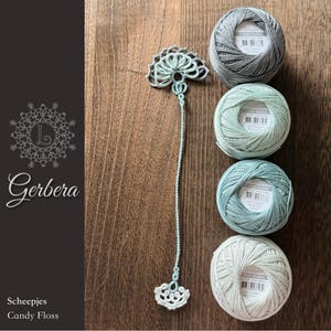 May include: A light green crocheted bookmark with a fan-shaped top and bottom, positioned next to four round balls of Scheepjes Candy Floss yarn in shades of grey, mint green, teal, and off-white, each featuring a white label with text.