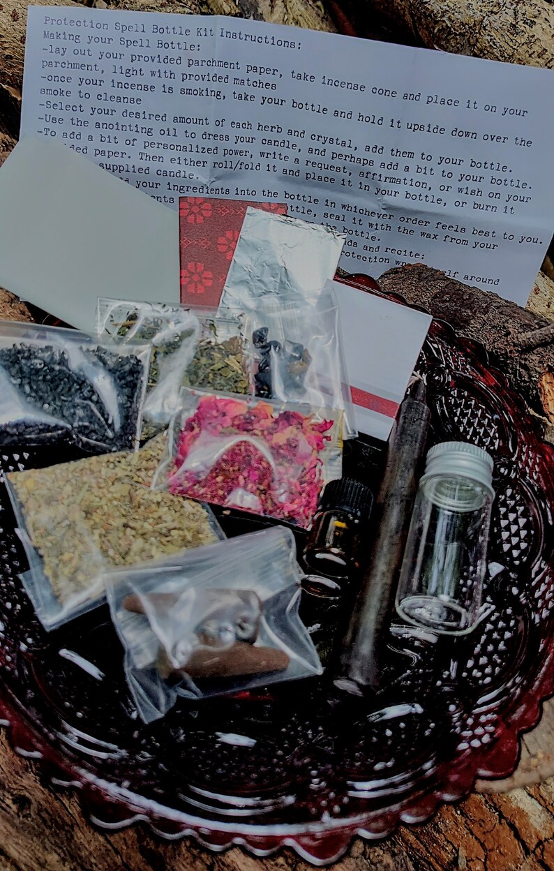 May include: A protection spell bottle kit with instructions on a white piece of paper. The kit includes a variety of herbs, crystals, a candle, and an anointing oil. The kit is on a red and black plate.