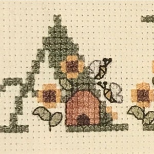 May include: Cross-stitch embroidery of the word "BEE" with a beehive and bees in a green and brown colour scheme.