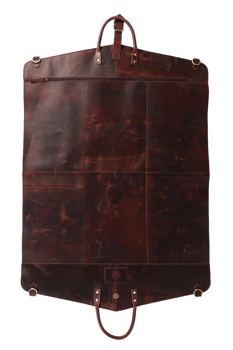 May include: A dark brown leather garment bag with a top handle and a bottom handle. The bag has a zipper closure and several metal accents. The leather has a distressed appearance.