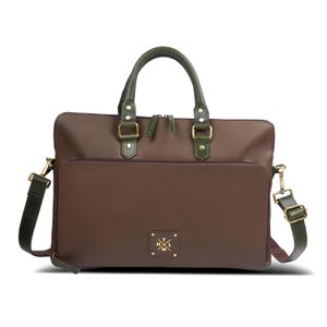Peut inclure: Une mallette marron avec des poignées en cuir vert foncé et une bandoulière assortie. Le sac présente une poche frontale zippée, des ferrures dorées et un petit écusson carré au centre avec les lettres H, T, L et W en forme de croix.