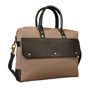 Peut inclure: Une mallette en toile taupe dotée d'un rabat noir texturé avec un logo central en relief, deux poignées supérieures noires et une bandoulière noire amovible. Le sac comprend des rivets et des ferrures en métal doré, avec des coins noirs.