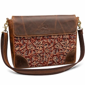 Può includere: Una borsa a tracolla in pelle marrone con una patta che riporta il logo River Roots Leather. Il pannello frontale presenta un tessuto rosso scuro con un fitto motivo floreale in nero, blu e crema. Include una tracolla regolabile in tessuto.
