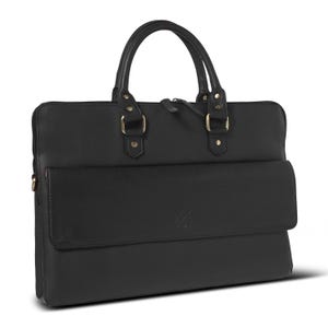 May include: A black leather briefcase featuring two top handles with gold-toned metal hardware, a zippered main compartment, and a front flap pocket with a subtle embossed logo. The bag has a structured rectangular shape with clean stitching.