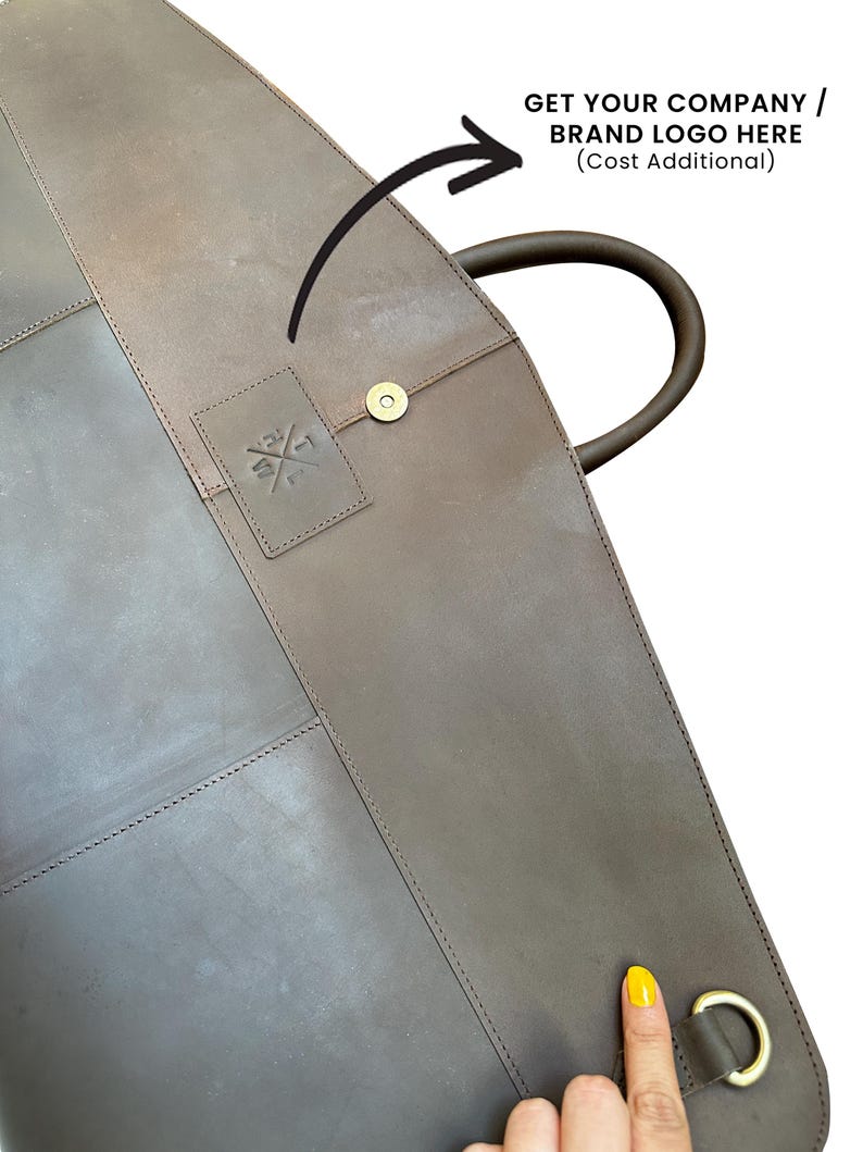 May include: A brown leather garment bag with a handle and a brass-colored clasp. The bag has a stitched design and a small embossed logo. The text "GET YOUR COMPANY / BRAND LOGO HERE" is also visible.