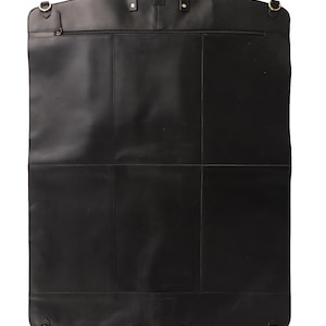 May include: A black leather garment bag with a top handle, a smaller handle at the bottom, and a zipper closure. The bag has gold-colored hardware and a rectangular shape with a curved top.