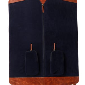 May include: A navy blue garment bag with brown leather accents. The bag features a full-length zipper, a top handle, and two small pockets. The bag has a brown leather trim at the top and bottom, with metal hardware.