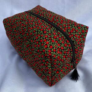 May include: A black zippered pouch with a red floral pattern. The pouch has a tassel zipper pull.