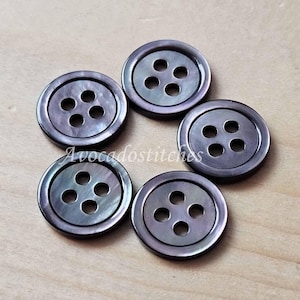 May include: Five black and iridescent shell buttons with four holes each. The buttons are round and have a smooth, polished finish.