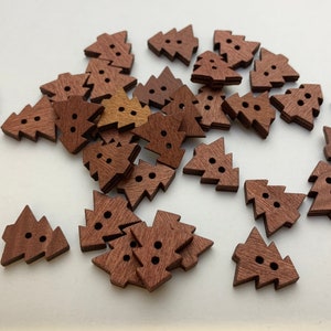 May include: A pile of brown wooden Christmas tree buttons. The buttons are approximately 2.5 cm in size and have a simple design.
