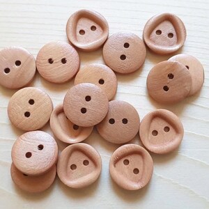 May include: A collection of 15 wooden buttons in various shapes and sizes. The buttons are all a light brown colour and have two or three holes.