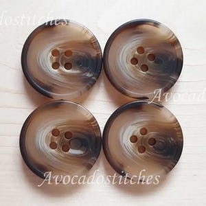 May include: Four brown and white swirl patterned buttons with four holes each.