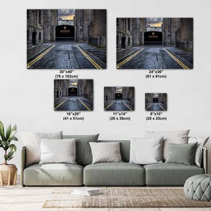 May include: A photo collage showing different sizes of a canvas print featuring a black and white photo of a narrow street with a stone archway and the words "Guinness" in gold lettering. The sizes are 30x40 inches, 24x36 inches, 16x20 inches, 11x14 inches, and 8x10 inches.