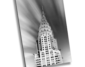 May include: A black and white photograph of the Chrysler Building in New York City. The building is tall and slender, with a distinctive Art Deco design. The sky is cloudy and the clouds are moving quickly.