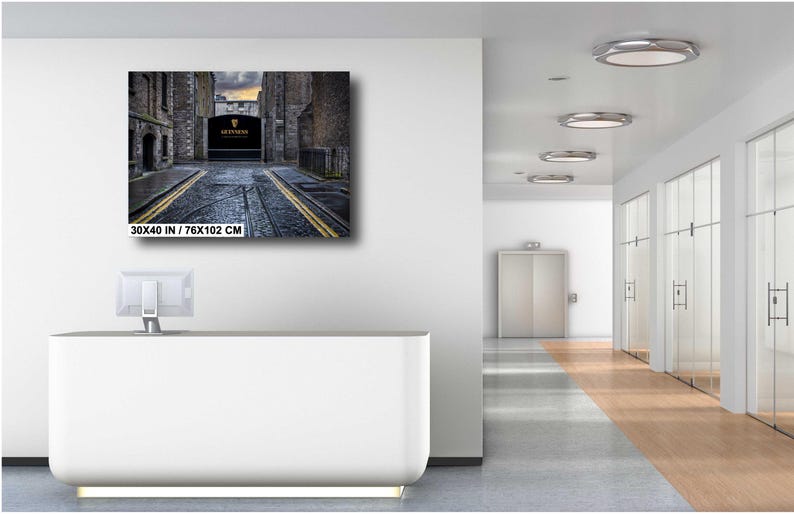 May include: A black and white photograph of a narrow street in a city. The street is lined with buildings on both sides, and there is a sign that reads "The Guinness Storehouse" at the end of the street.