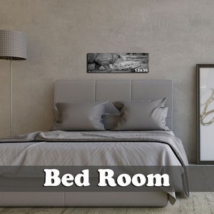 May include: A gray upholstered bed with white bedding in a bedroom setting. A black and white photograph of a rhinoceros is hanging on the wall above the bed. The photo is 12 inches by 36 inches.