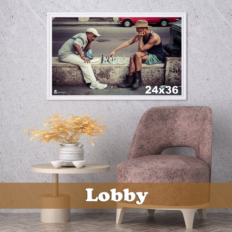 May include: Two men play chess on a street in Havana, Cuba. One man wears a straw hat and the other wears a baseball cap. The chessboard is set up on a stone wall.