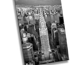 May include: Black and white aerial photograph of a skyscraper in New York City. The Chrysler Building is visible in the center of the image, with other buildings surrounding it. The photo was taken from a high vantage point, giving a bird's-eye view of the city.