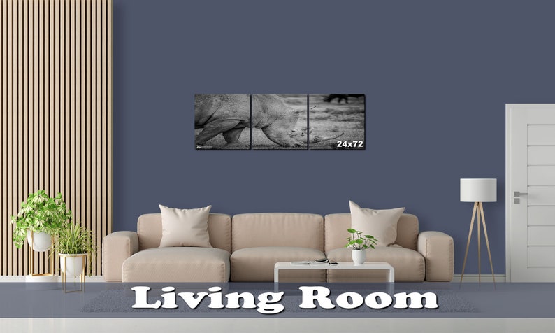 May include: A black and white photograph of a rhinoceros in a living room setting. The photo is split into three panels and is hung above a beige couch. The photo is 24 inches by 72 inches.