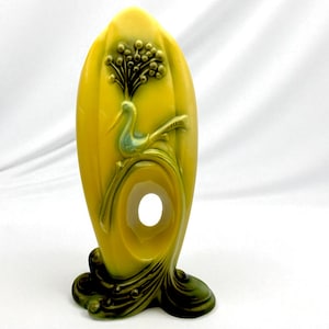 Può includere: Vaso giallo art déco con un design di uccelli e fiori. Il vaso ha una grande forma ovale con un foro al centro. L'uccello è azzurro e il motivo floreale è verde scuro.