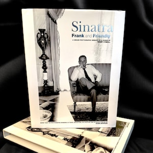 May include: A black and white photo of Frank Sinatra sitting in a chair. The book cover reads "Sinatra Frank and Friendly A Unique Photographic Memoir of a Legend by Terry O'Neill".