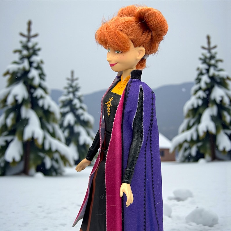 Side profile of Anna Frozen II doll showing auburn hair bun, layered cape colors, and dress details