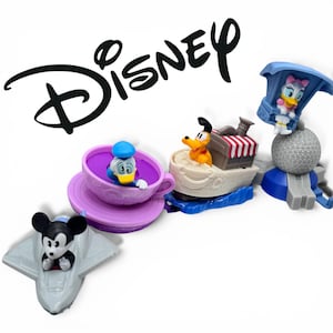 Könnte beinhalten: Eine Sammlung von Disney-Charakterspielzeugen, darunter Mickey Mouse in einem grauen Flugzeug, Donald Duck in einer lila Tasse, Pluto auf einem Boot und Daisy Duck in einem blauen Fahrgeschäft. Das Disney-Logo ist schwarz im Hintergrund.