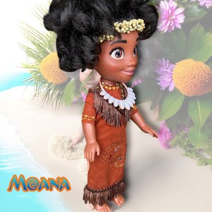 Moana doll viewed from the side, posed near the ocean edge. Her handmade outfit and intricate accessories are shown with flowers and greenery in the background.