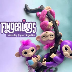 Puede incluir: Tres juguetes de mono morados y rosas con el texto Fingerlings friendship @ your fingertips. Un mono cuelga de una rama negra, mientras que otros dos están colocados debajo. Los monos tienen caras, orejas y manos de color claro.
