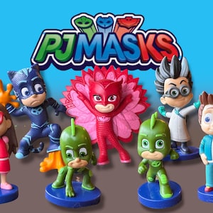 Puede incluir: Colección de figuras de personajes de PJ Masks. Las figuras incluyen a Gatuno, Gekko, Buhíta y otros, cada uno con disfraces y poses distintos. El logotipo de PJ Masks se muestra encima de las figuras sobre un fondo azul.