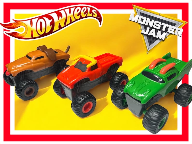 Puede incluir: Tres camiones de juguete Hot Wheels Monster Jam. Los camiones son naranja, rojo y verde. Los camiones tienen ruedas grandes y est&aacute;n dise&ntilde;ados para parecerse a los monster trucks. Los camiones est&aacute;n sobre un fondo amarillo. Los logotipos de Hot Wheels y Monster Jam son visibles en la imagen.