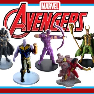 Puede incluir: Una colección de figuras de Marvel Avengers, que incluye a Pantera Negra, Thanos, Ojo de Halcón, Loki y Spider-Woman. El logotipo de los Vengadores se muestra encima de las figuras. Las figuras están sobre bases individuales y son de colores brillantes.
