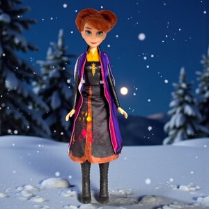 Anna Frozen II light-up doll shown at night-style snowy background with illuminated skirt pattern visible through dress fabric